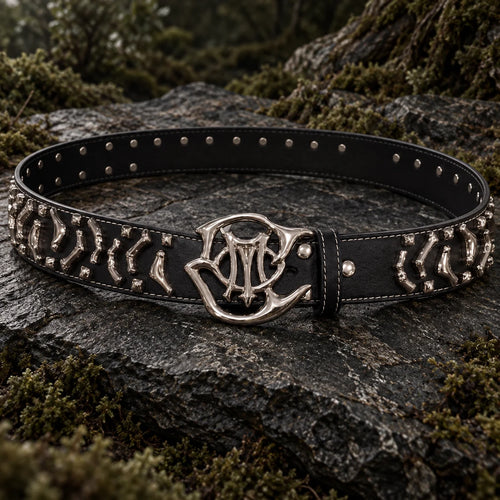Black leather Orion Belt with polished sculpted hardware on moss-covered rock.